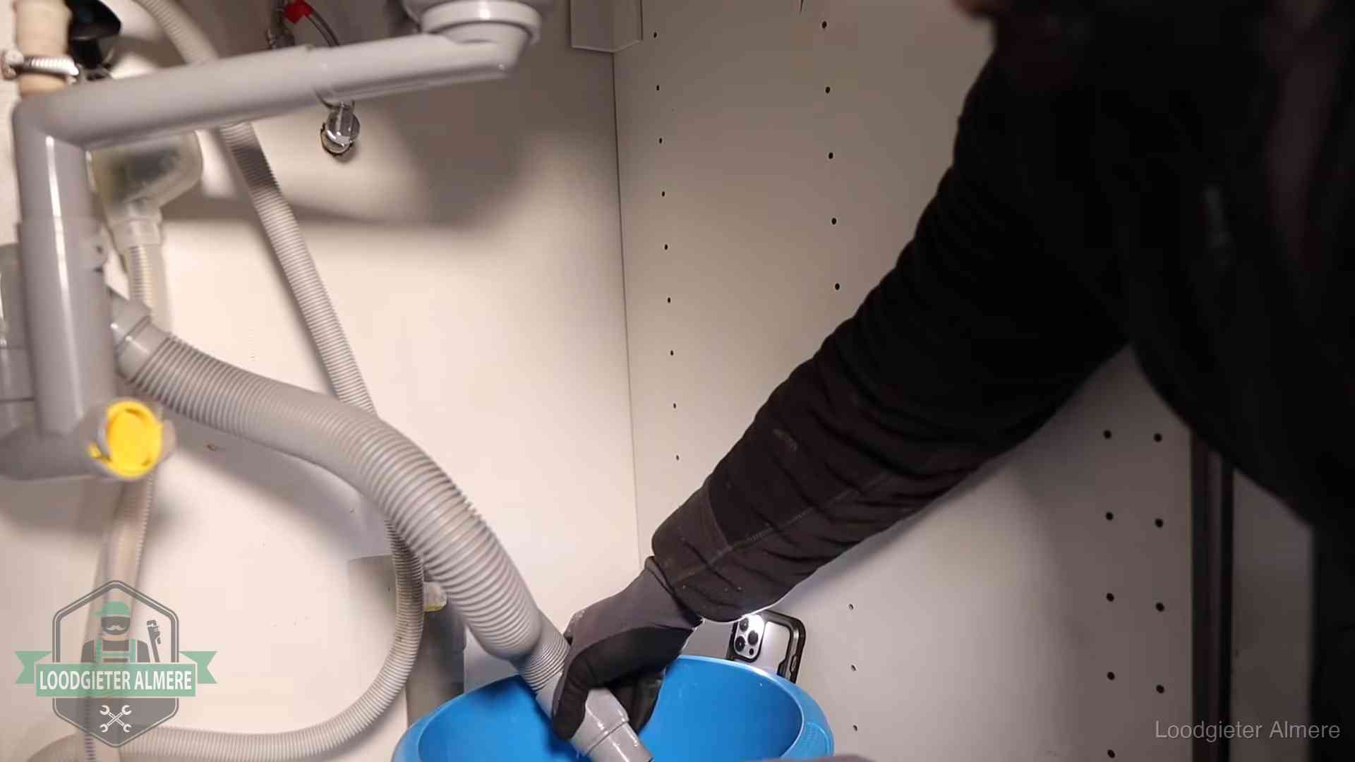 Afvoerslang loopt leeg in een emmer onder de gootsteen in Almere, een klus die je zelf kunt doen