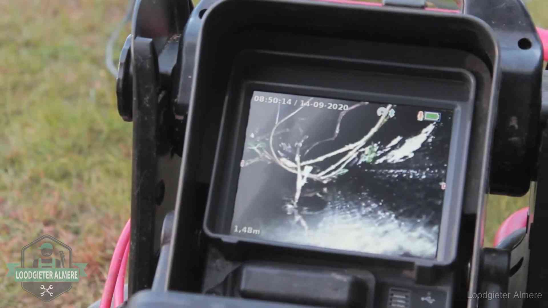 Monitor van een rioolcamera toont wortelingroei in de rioolbuis bij een woning in Almere