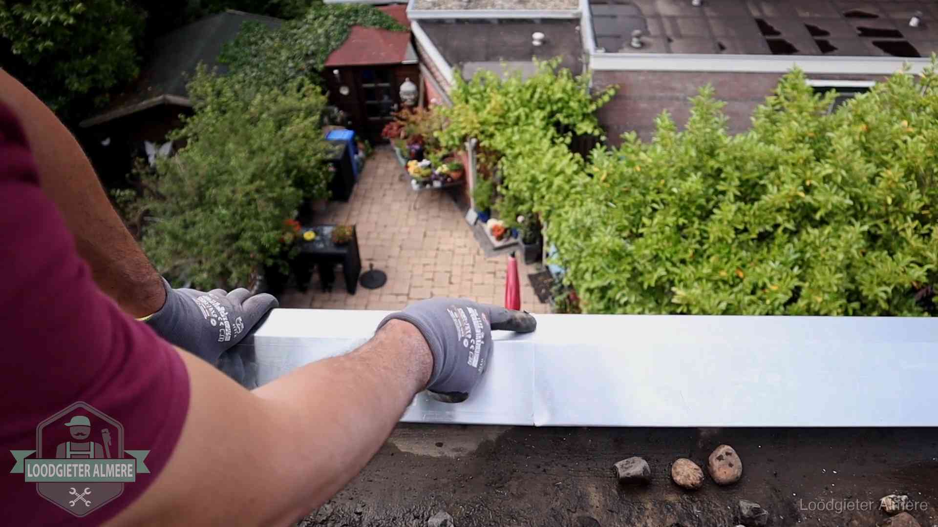 Daklekkage geregeld in Almere Vakman plaatst een daktrim op de dakrand van een woning in Almere
