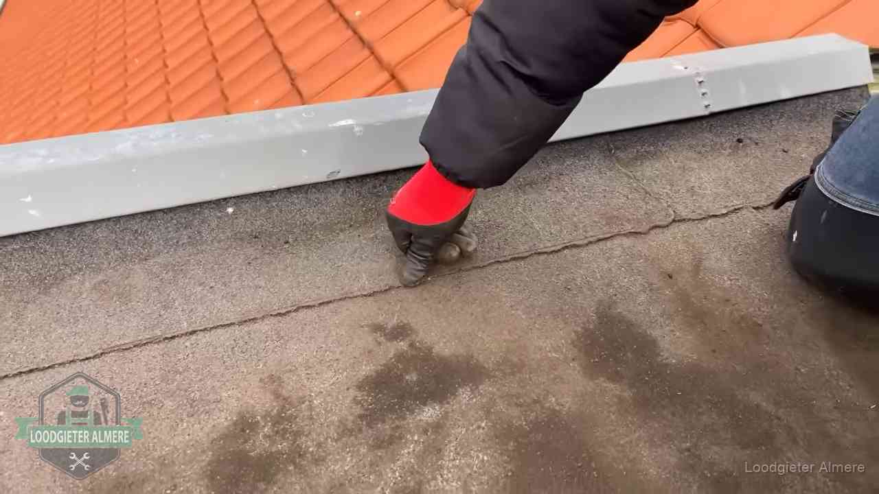 Lekkage bij de naad van een plat dak in Almere Vakman wijst een naad met vochtplekken aan op een bitumen plat dak in Almere