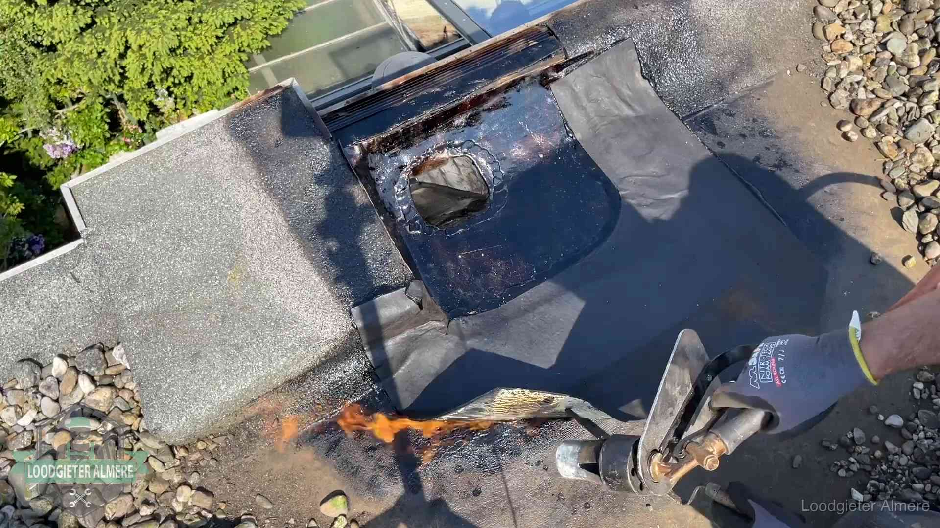 Daklekkage repareren in Almere Dakdekker brandt bitumen rond een doorvoer tijdens een daklekkage-reparatie in Almere
