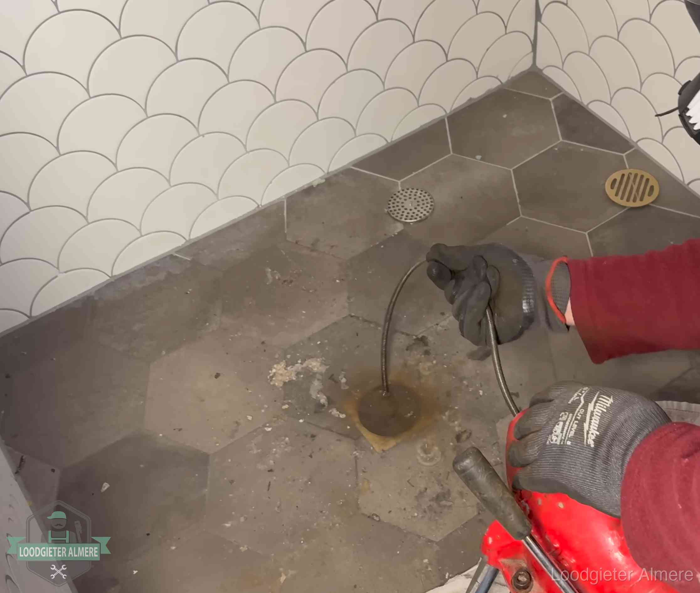 Ontstoppingsveer gaat in een geopend doucheputje in Almere waar het water omhoogkwam