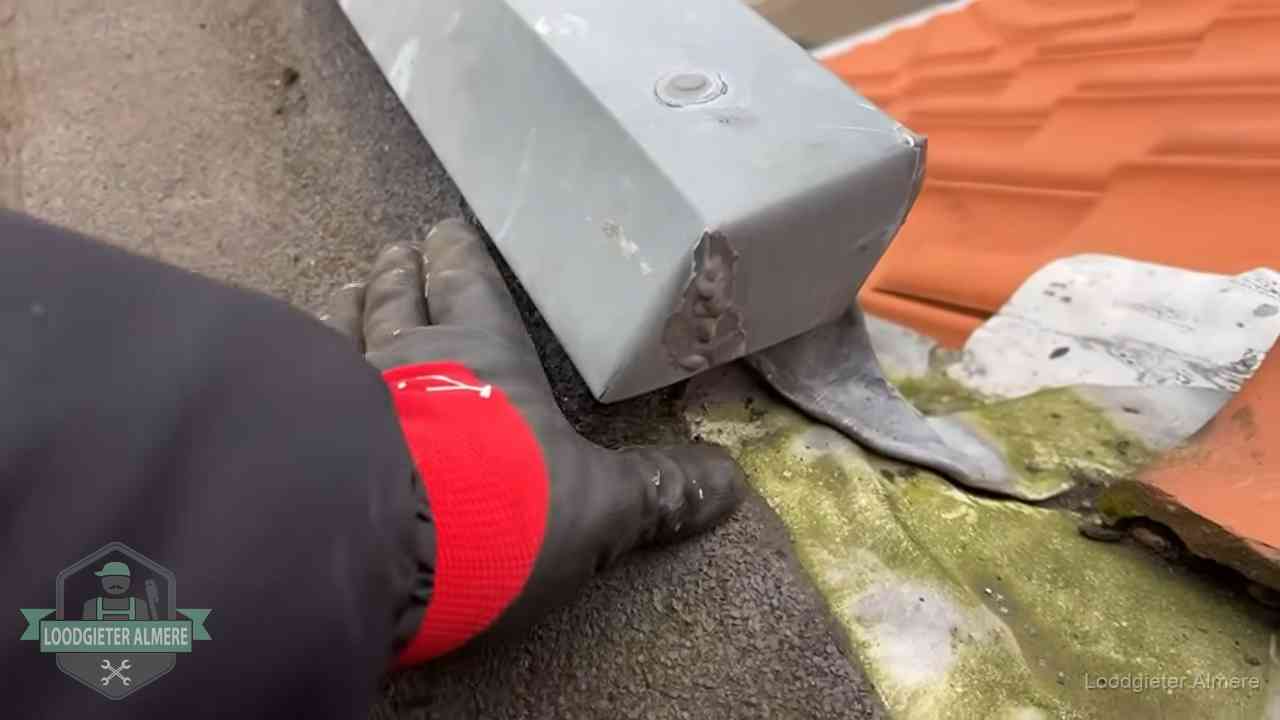 Hemelwaterafvoer en dakgoot controleren in Almere Controle van een zinken hemelwaterafvoer met loodslab bij dakpannen in Almere