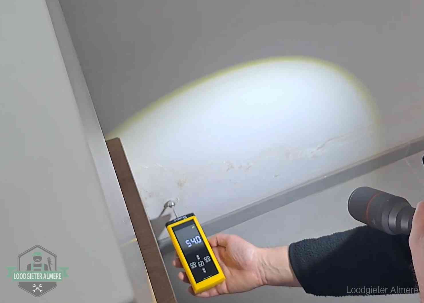 Vochtmeter tegen een natte wand met lekkagesporen in Almere