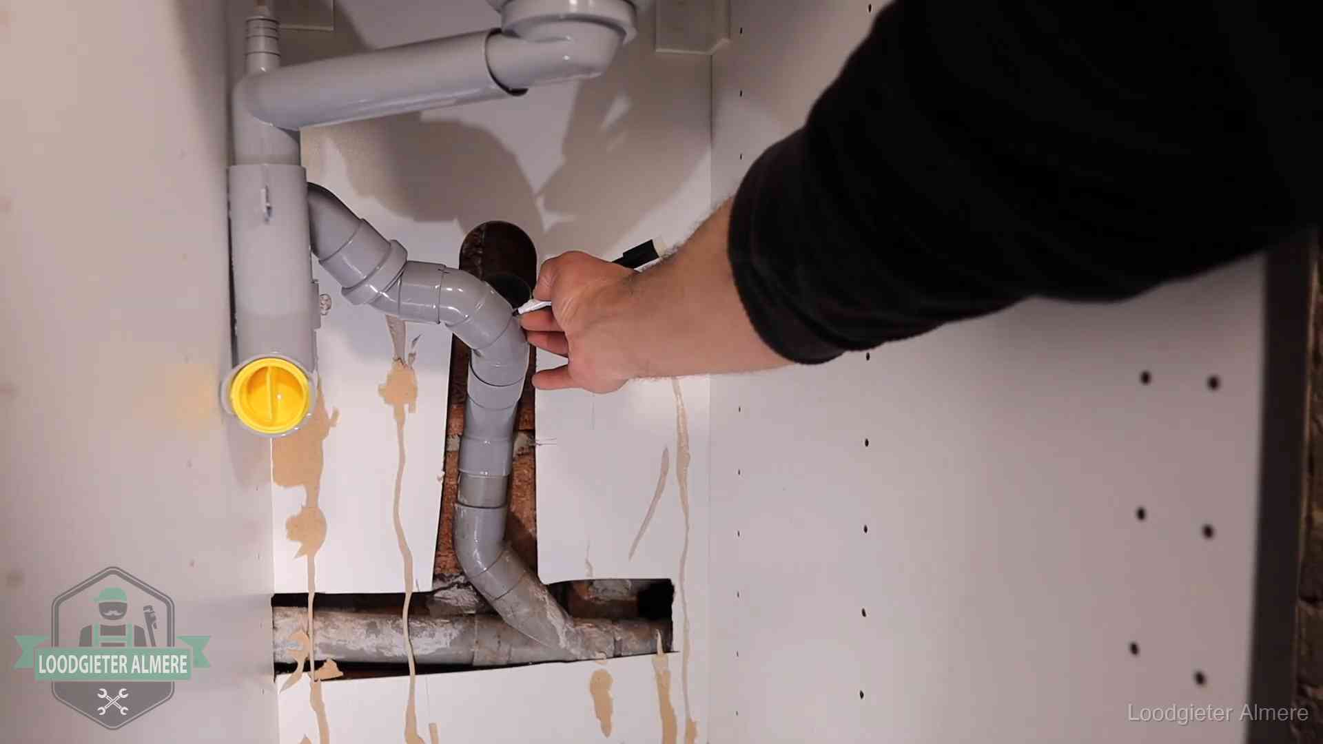 Loodgieter markeert een pvc-afvoerbuis onder een gootsteen in Almere