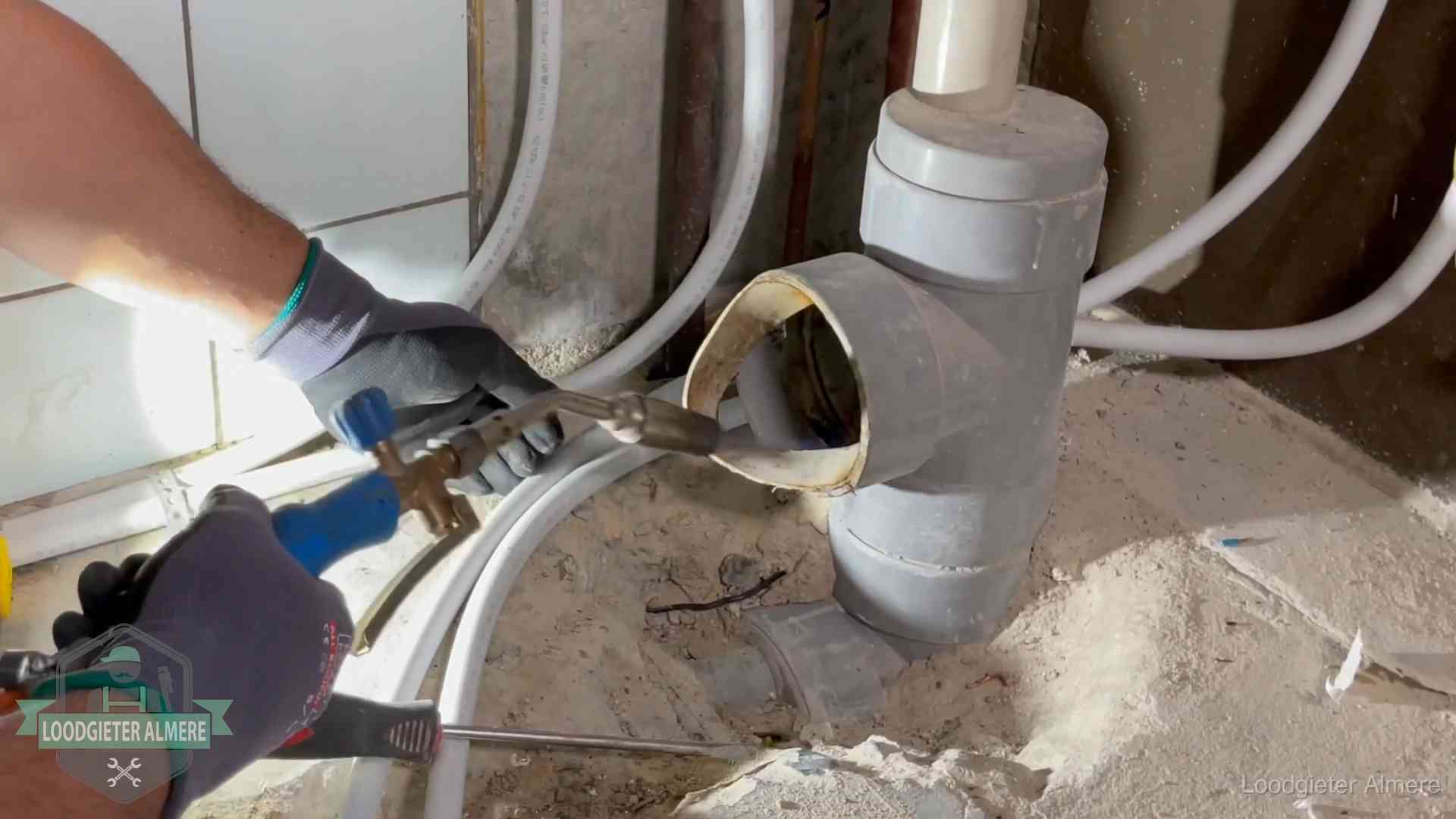 Loodgieter werkt met brander en messing kraanwerk aan leidingen in Almere