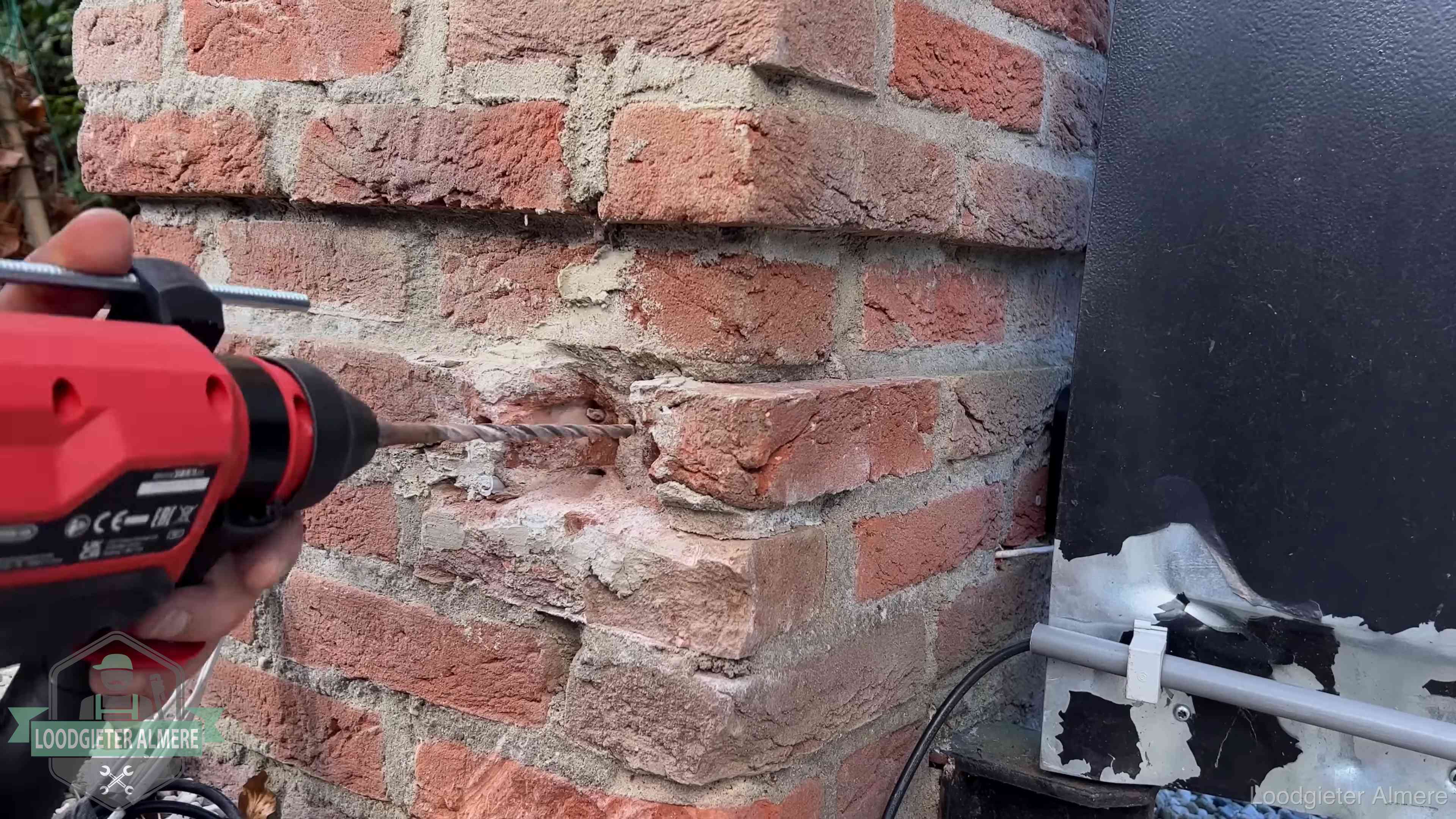Vakman boort in de buitenmuur van een woning in de regio Almere