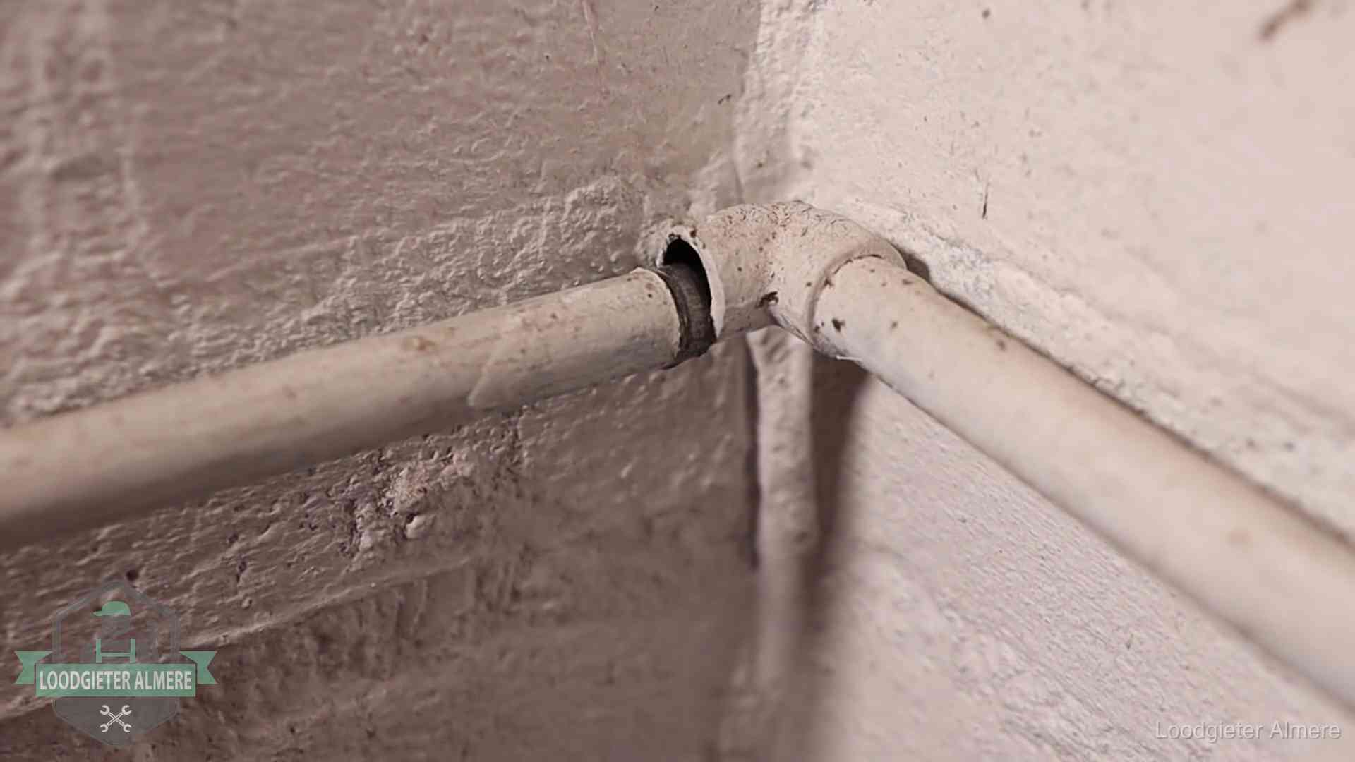 Oude geverfde waterleiding met een losliggende fitting in een woning in Almere
