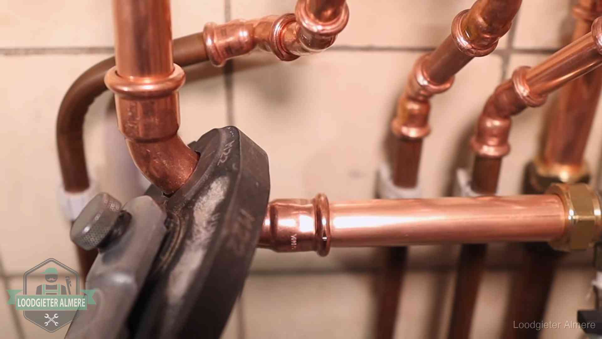 Persmachine perst een koperen fitting op nieuw leidingwerk in Almere