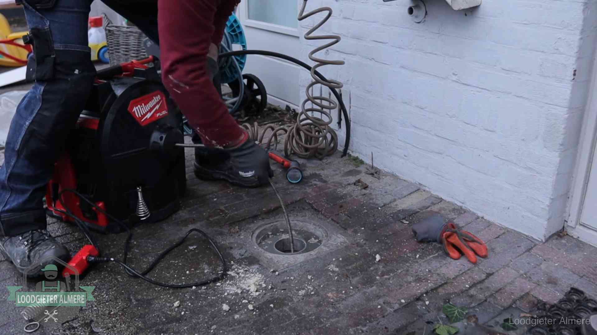 Spiraalmachine bij een ontstoppingsputje in de bestrating in Almere