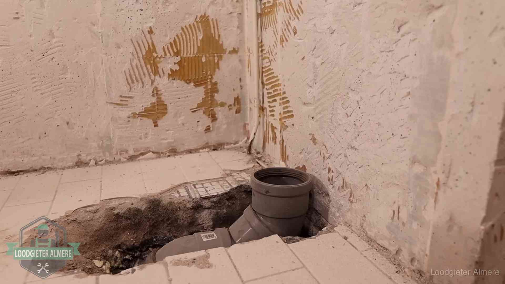 Opengebroken vloer met een nieuwe pvc-rioolbocht in een gegraven sleuf in Almere