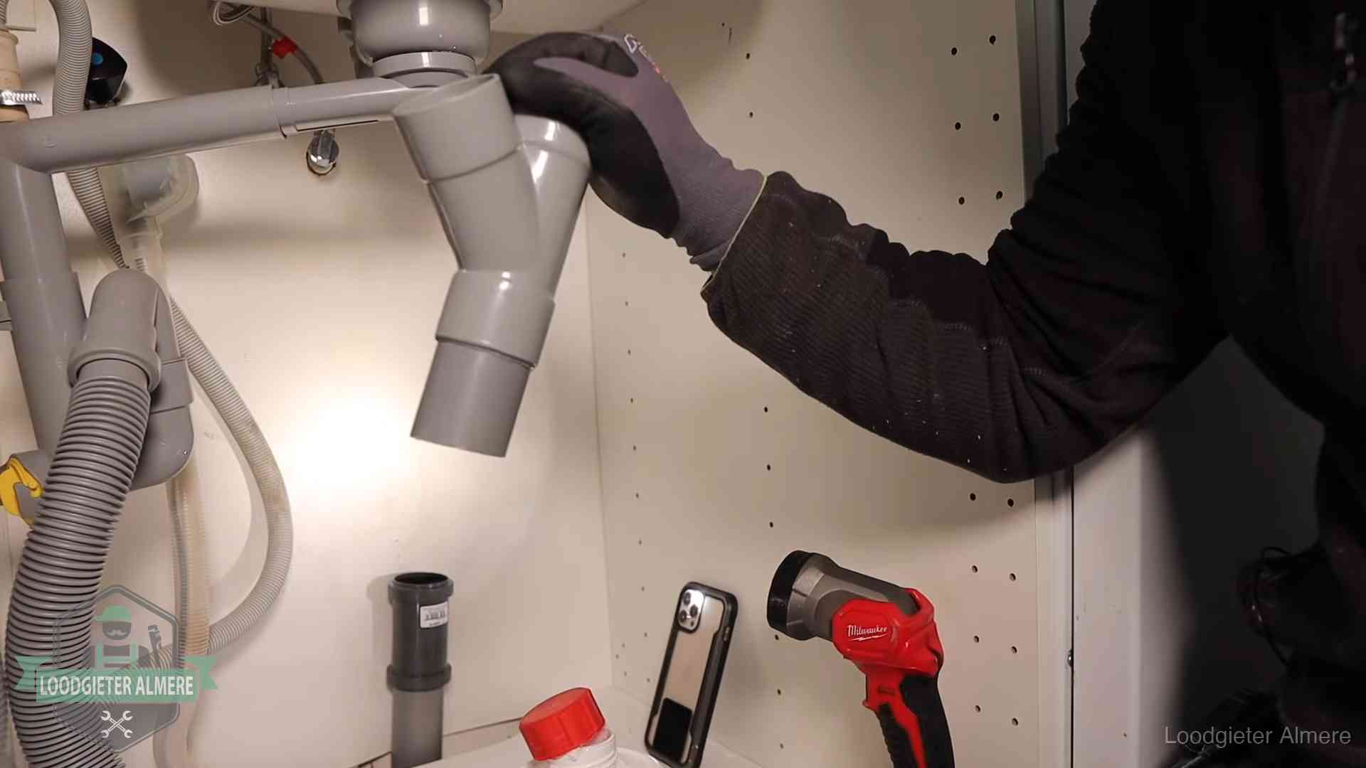Loodgieter demonteert het sifon- en afvoerwerk onder een gootsteen in Almere bij stankklachten