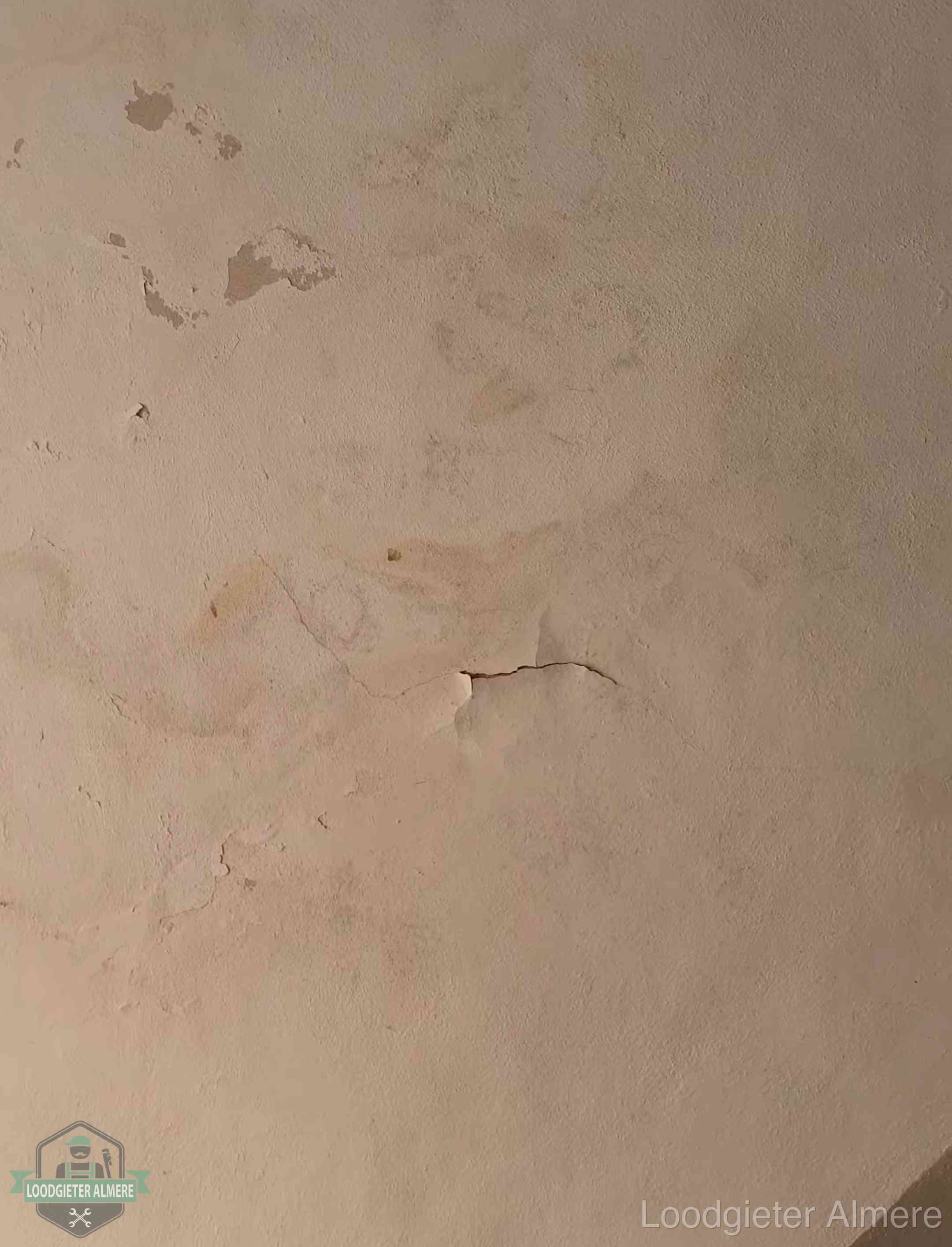 Vochtkringen en afbladderende verf op een plafond in Almere, schade voor het meetrapport en de verzekering